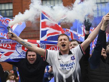 Para fans Glasgow Rangers menyalakan granat asap di luar Ibrox Stadium (7/3/2021) untuk merayakan keberhasilan tim kesayangan mereka merebut gelar Liga Utama Skotlandia setelah memimpin 20 poin dari saingan terdekat, Glasgow Celtic. (AFP/Andy Buchanan)