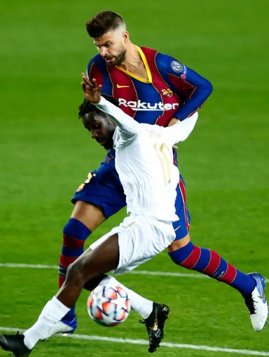 Bek Barcelona, Gerard Pique berusaha menghentikan pemain Ferencvaros, Tokmac Nguen Ferencvaros pada laga pertama Grup G Liga Champions 2020-2021 di Camp Nou, Rabu (21/10/2020) dini hari WIB. Main dengan 10 pemain, Barcelona mampu mencukur Ferencvaros 5-1. (AP Photo/Joan Monfort)