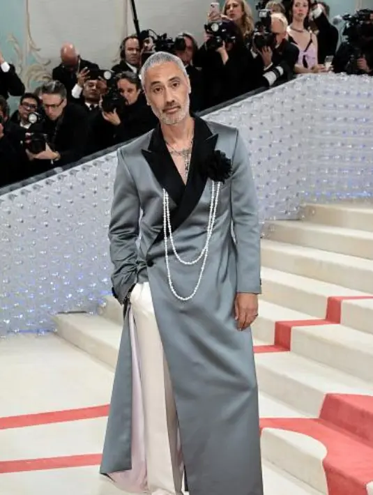 Tak ingin kalah dengan sang istri, Taika Waiti juga bersinar dengan aksesori Cartier. Ia kenakan jam tangan Cartier Santos-Dumont dan kalung Panthere de Cartier. [Cartier]