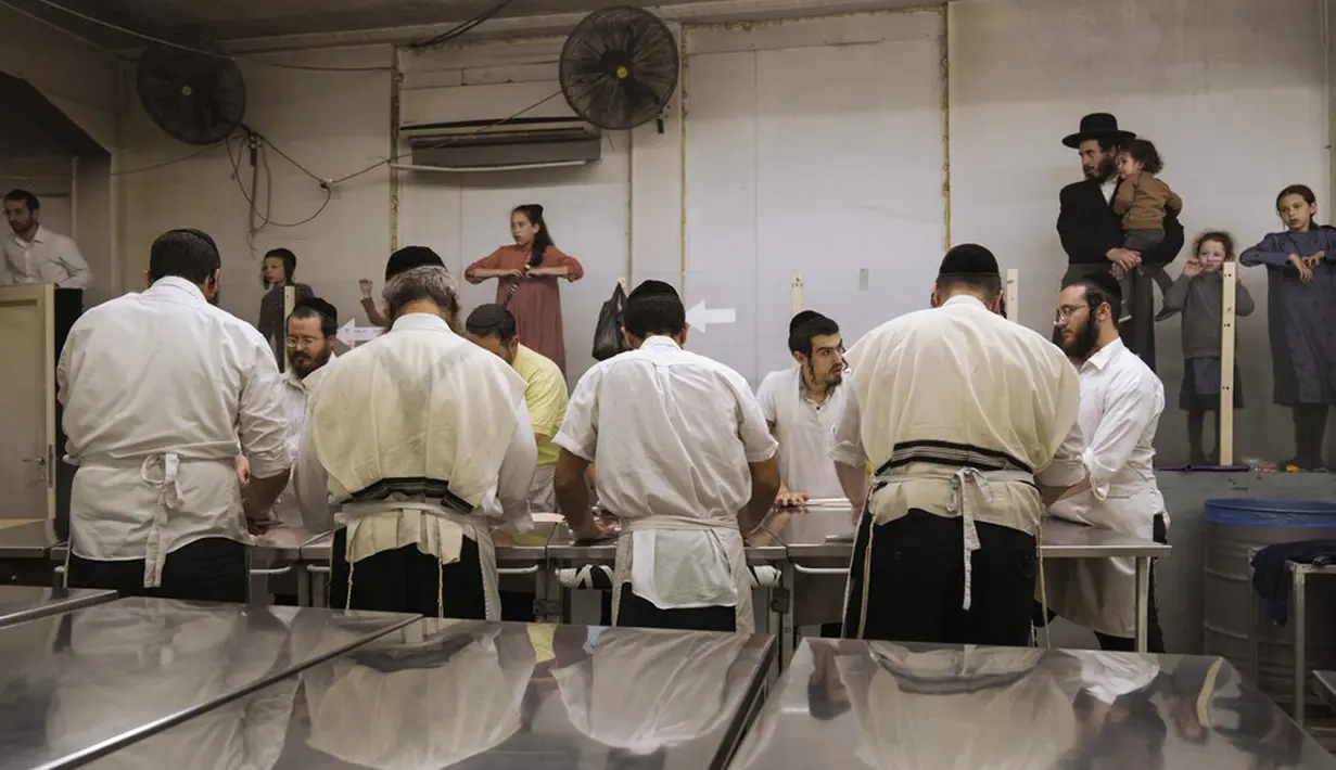 Yahudi Ultra-Ortodoks menyiapkan matzoh khusus di sebuah toko roti di Ashdod, Israel, 11 April 2022. Orang Yahudi dilarang makan makanan beragi selama liburan Paskah merayakan kisah alkitabiah tentang bangsa Israel saat melarikan diri dari perbudakan dan eksodus dari Mesir. (AP Photo/Tsafrir Abayov)