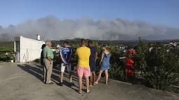 Orang-orang melihat ke arah kebakaran hutan terdekat di distrik Landal Caldas da Rainha di Portugal, Rabu (17/8/2022). Namun, para pejabat memperingatkan perkiraan gelombang panas baru untuk daerah tersebut dapat memperumit tugas tersebut. (AP Photo/Joao Henriques)