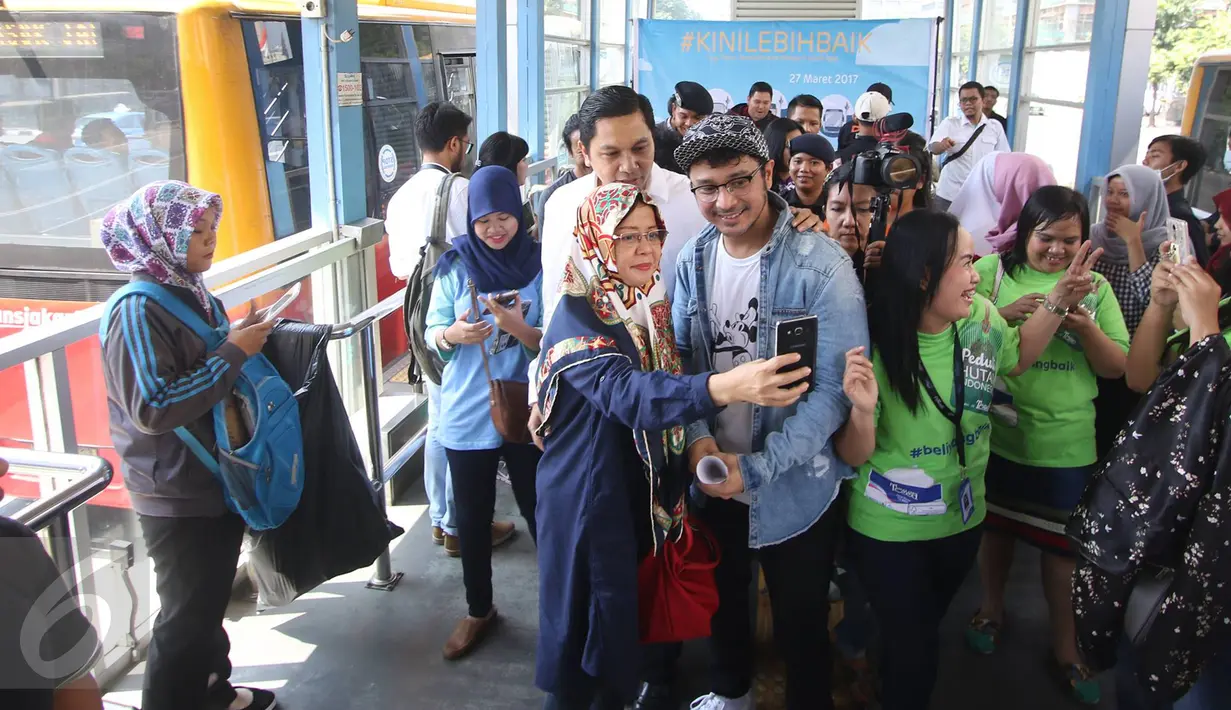 Penumpang foto bersama dengan vokalis grup musik Nidji, Giring di Halte Transjakarta Sarinah, Thamrin, Jakarta Pusat, Senin (27/3). Acara tersebut diadakan dalam rangka memperingati ulang tahun ke-3 PT Transjakarta. (Liputan6.com/Immanuel Antonius)