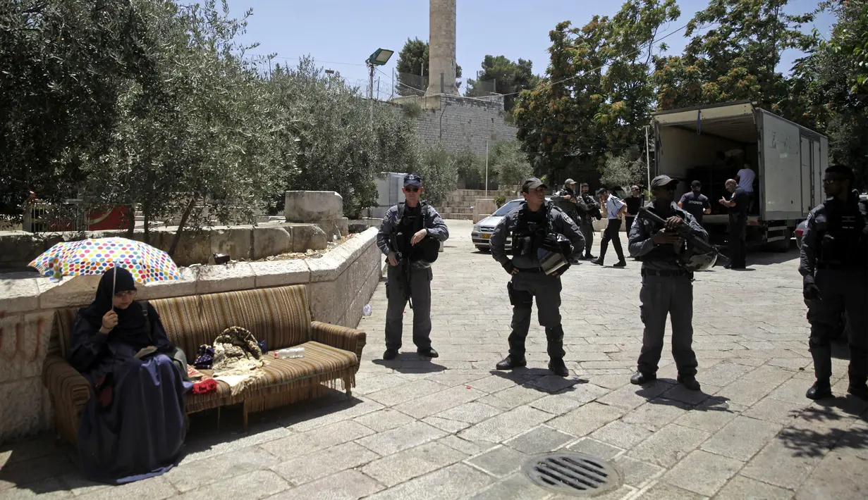 Petugas Israel melakukan penjagaan terhadap wanita muslim yang duduk di luar komplek Masjid Al- Aqsa, Yerusalem, Minggu (16/7). Setelah pekan lalu terjadi kerusuhan antara warga Arab-Israel dengan petugas kepolisian Israel. (AP/Mahmoud Illean)