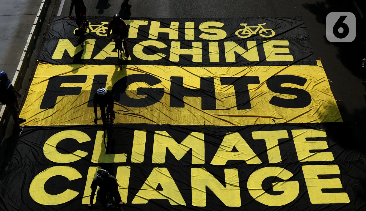 Pesepeda melintas di atas banner yang dibentangkan aktivis Greenpeace dan Bike2Work di Jalan Jenderal Sudirman, Jakarta, Minggu (5/6/2022). Aksi untuk mengkampanyekan penggunaan sepeda sebagai kendaraan ramah lingkungan dan solusi pembangunan Jakarta Kota Ramah Pesepeda. (Liputan6.com/Helmi Fithriansyah)