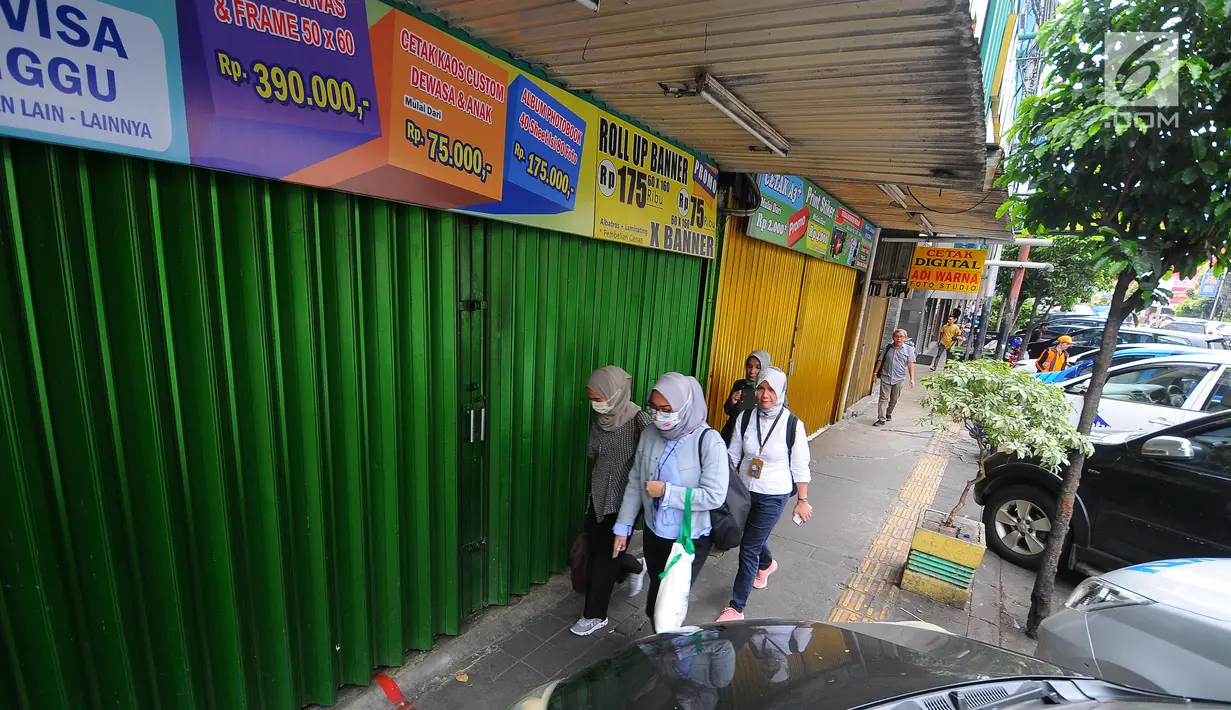Pejalan kaki melintas di depan pertokoan yang tutup di Jalan Sabang, Jakarta pada Rabu (22/5/2019). Pemilik toko dan pengelola kantor di kawasan tersebut menutup toko dan kantor mereka imbas aksi 22 Mei 2019 yang berakhir rusuh di beberapa titik lokasi. (Liputan6.com/Aangga Yuniar)