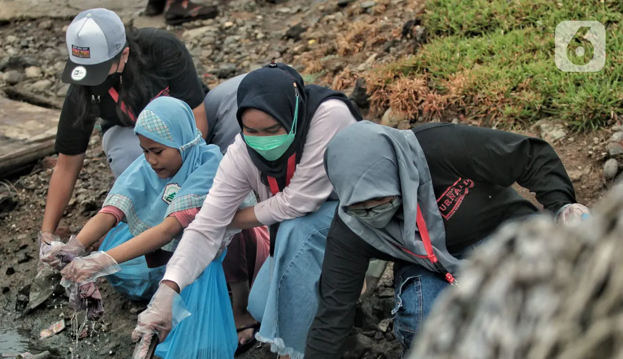 Sukarelawan Kelas Jurnalis Cilik saat membersihkan sampah di kawasan Cilincing, Jakarta Utara, Minggu (5/12/2021). Kegiatana ini guna mengurangi sampah yang berdatangan akibat banjir rob. (merdeka.com/Iqbal S. Nugroho)