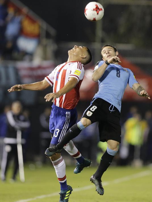 Gelandang Uruguay, Nahitan Nandez, berebut bola dengan bek Paraguay, Junior Alonso, pada laga kualifikasi piala dunia 2018 di Stadion Defensores del Chaco, Rabu (6/9/2017). Uruguay menang 2-1 atas Paraguay. (AP/Jorge Saenz)