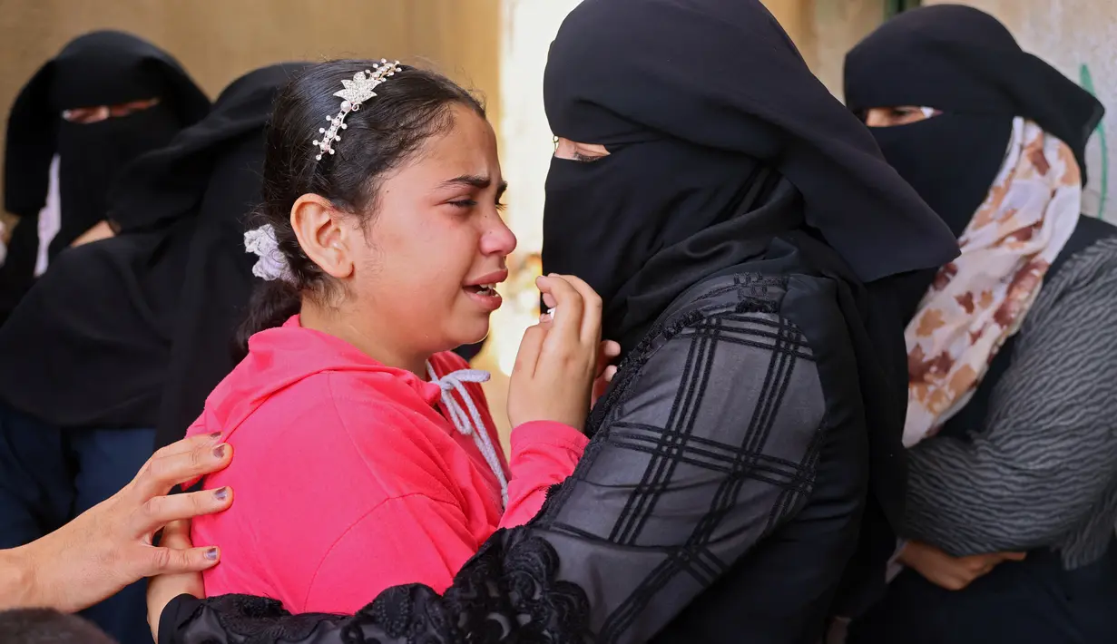 Kerabat berduka selama pemakaman Tareq al-Qadi, yang tewas sehari sebelumnya dalam serangan udara Israel, di Rafah, Jalur Gaza selatan, Senin (17/5/2021). Tercatat, ada 212 penduduk Jalur Gaza, Palestina kehilangan nyawa di antaranya 61 korban merupakan anak-anak. (SAID KHATIB/AFP)