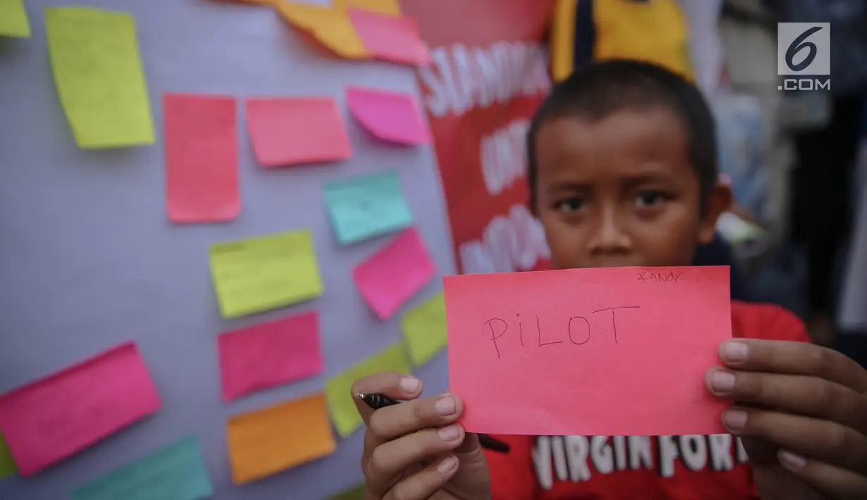 Seorang anak menunjukan tulisan cita-citanya  di jalur banjir kanal barat Tanah Abang, Jakarta, Senin (31/7). Kegiatan tersebut sebagai bentuk harapan mereka dalam rangka peringati hari anak nasional. (Liputan6.com/Faizal Fanani)