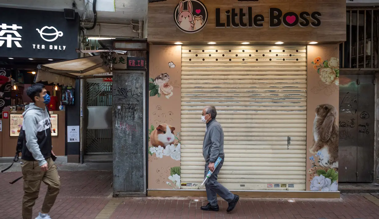 Seseorang melewati toko hewan peliharaan tempat seorang karyawan dan pelanggan dinyatakan positif Covid-19 setelah menangani hamster di Causeway Bay, Hong Kong pada 18 Januari 2022,  memicu rencana pemusnahan lebih dari 1.000 hewan kecil usai beberapa hamster dinyatakan positif. (Bertha WANG/AFP)