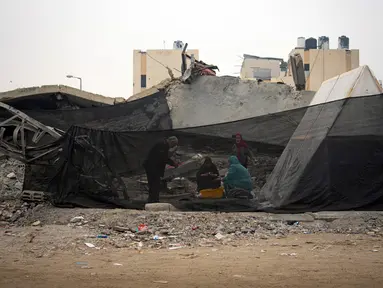 Warga Palestina yang mengungsi akibat bombardir Israel terhadap Jalur Gaza memasak di tenda kamp darurat di kawasan Muwasi, Kamis (28/12/2023). (AP Photo/Fatima Shbair)