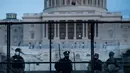 Petugas Kepolisian Capitol berjaga bersama pasukan Garda Nasional di belakang pagar pengendali kerumunan di sekitar Capitol Hill AS di Washington, Kamis (7/1/2021). Peristiwa penyerbuan di gedung Capitol Hill AS dilakukan oleh massa pendukung Donald Trump pada 6 Januari. (Brendan Smialowski/AFP)