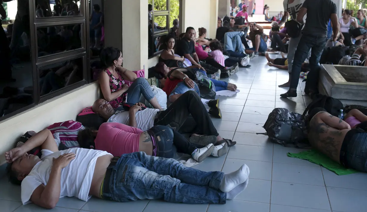 Sejumlah imigran Kuba beristirahat di luar gedung bea cukai di perbatasan antara Nikaragua dan Kosta Rika, Minggu (15/11). Nikaragua menutup perbatasannya dengan Kosta Rika hingga ribuan orang yang menuju Amerika terlantar. (REUTERS/Oswaldo Rivas)