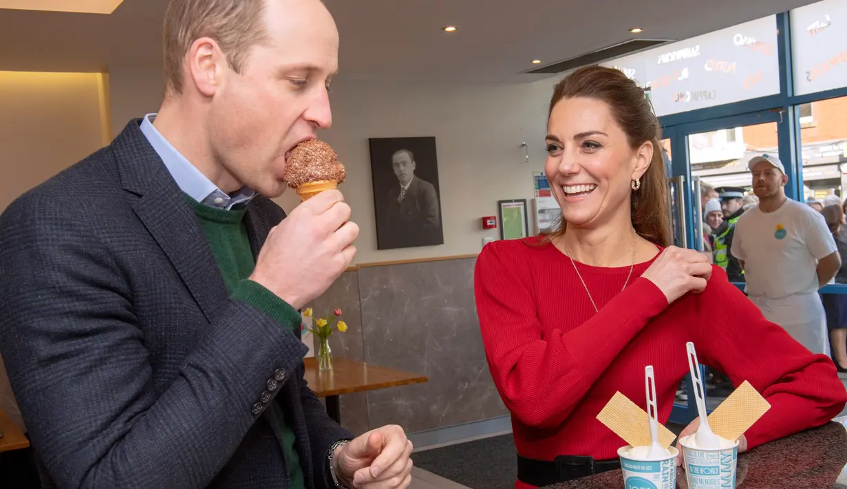 Kate Middleton tersenyum melihat Pangeran William mencicipi es krim saat mengunjungi Joe's Ice Cream di kawasan Mumbles, Wales Selatan, Selasa (4/2/2020). Dalam kesempatan yang sama, William dan Kate juga menyambangi para sukarelawan di salah satu stasiun sekoci penyelamat. (ARTHUR EDWARDS/POOL/AFP)