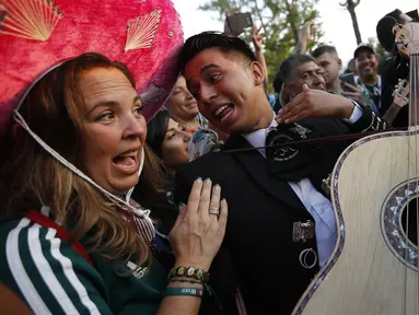 Suporter Meksiko memainkan gitar saat merayakan kemenangan timnya atas Jerman pada Piala Dunia 2018 di Luzhniki Stadium, Moskow, (17/6/2018). Meksiko menan 1-0. (AP/Alexander Zemlianichenko)