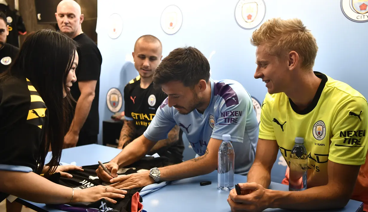 Pemain Manchester City David Silva, Angelino dan Oleksandr Zinchenko menandatangani jersey penggemar selama acara promosi di Hong Kong (23/7/2019). The Citizens akan menghadapi Kitchee SC dalam laga uji cobadi Hong Kong Stadium pada 24 Juli 2019. (AFP Photo/Anthony Wallace)