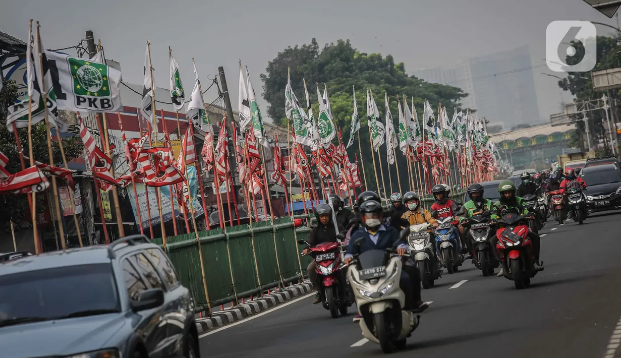 Pengendara melintas di dekat bendera parpol yang terpasang di pembatas jalan kawasan Tebet, Jakarta, Selasa (25/7/2023). (Liputan6.com/Faizal Fanani)
