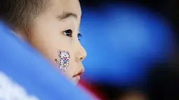 Seorang anak memakai salah satu maskot Olimpiade di wajahnya saat menonton perlombaan speedskating 1.500 meter putri di Gangneung Oval pada Olimpiade Musim Dingin PyeongChang 2018 di Gangneung, Korea Selatan, 12 Februari 2018. (AP Photo/John Locher)