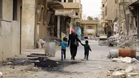 Seorang ibu bersama anaknya kembali ke rumah mereka di kota modern Palmyra, berdekatan dengan kota kuno Suriah, Sabtu (9/4). Kota itu berhasil direbut kembali oleh militer Suriah dari tangan kelompok ekstrimis ISIS beberapa waktu lalu. (Louai BESHARA/AFP)