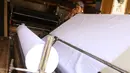 Pedagang menggulung bahan kain yang akan dijual di kawasan Tangerang, Banten, Sabtu (25/9/2021). Kementerian Perindustrian memberikan stimulus bagi industri tekstil dalam negeri berupa program Restrukturisasi Mesin/Peralatan Industri Penyempurnaan dan Percetakan Kain. (Liputan6.com/Angga Yuniar)