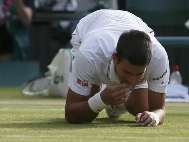 Petenis Novak Djokovic memakan rumput lapangan usai memastikan diri menjadi juara Wimbledon, London, Minggu (6/7/14). (REUTERS/Stefan Wermuth)