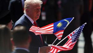 Presiden Donald Trump mengangkat bendera Malaysia dan Amerika Serikat dalam upacara penyambutan setibanya di Bandara Internasional Kuala Lumpur, Minggu (26/10/2025) untuk menghadiri KTT ke-47 ASEAN. (Dok. Hasnoor Hussain/Pool Photo via AP)&nbsp;&nbsp;&nbsp;