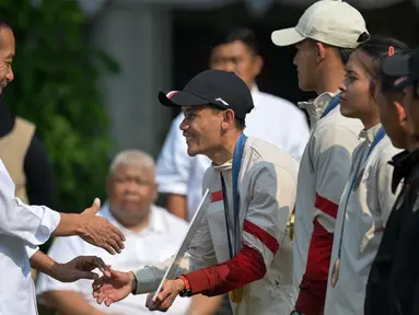 Presiden Joko Widodo menyalami peraih medali emas Indonesia di cabang olahraga panjat tebing Olimpiade Paris 2024, Veddriq Leonardo saat upacara penerimaan yang dilakukan di Istana Merdeka, Jakarta, pada Kamis 15 Agustus 2024. (BAY ISMOYO/AFP)