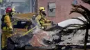 Petugas pemadam kebakaran berada di lokasi jatuhnya sebuah pesawat kecil jatuh di Santee, California, Senin (11/10/2021). Pesawat tersebut menabrak dua rumah dan menimbulkan ledakan yang membakar truk yang sedang melewati jalan. (AP Photo/Gregory Bull)