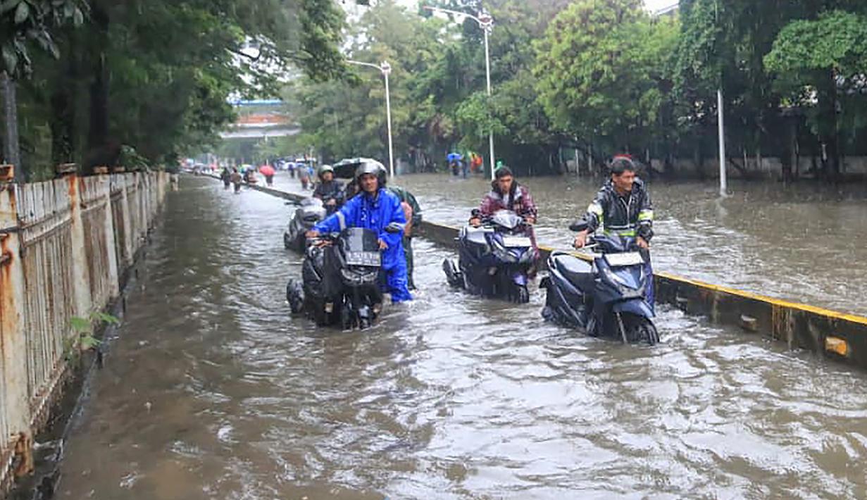 Genangan air tampak merendam beberapa ruas jalan utama, salah satunya Jalan Jembatan Tiga Raya di Jakarta Utara. Tampak dalam foto, pengendara terpaksa mendorong motornya yang mogok saat melintasi banjir yang menggenangi Jalan Jembatan Tiga Raya, Jakarta Utara, Senin (12/1/2026). (merdeka.com/Arie Basuki)