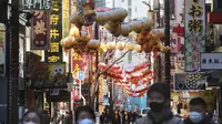 Orang-orang yang memakai masker berjalan di bawah pernak-pernik Imlek saat melintasi Chinatown di Yokohama, Prefektur Kanagawa, dekat Tokyo, Selasa (9/2/2021). Yokohama Chinatown adalah kawasan pecinan terbesar di Jepang, terletak di pusat kota Yokohama. (AP Photo/Koji Sasahara)