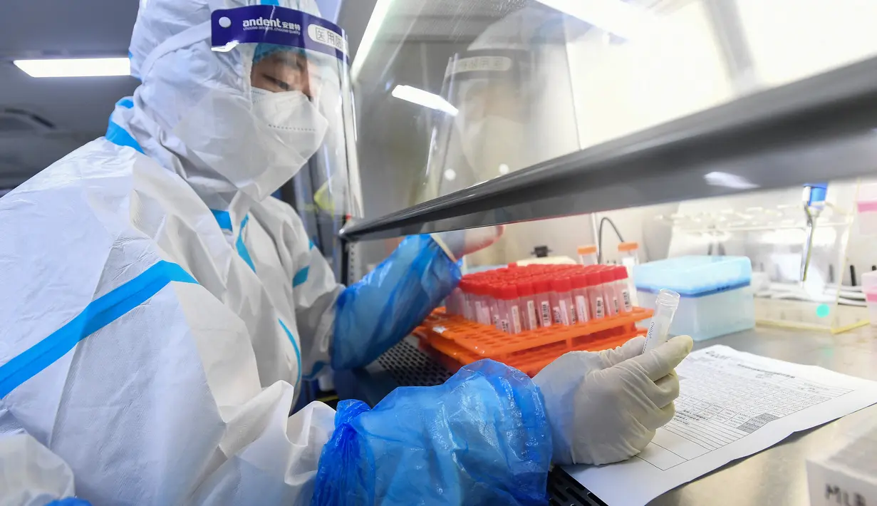 Seorang teknisi laboratorium yang mengenakan alat pelindung diri (APD) bekerja pada sampel yang akan diuji untuk virus corona Covid-19 di laboratorium Mata Api, fasilitas pengujian Covid-19, di Wuhan di provinsi Hubei tengah China (5/8/2021). (AFP/STR)