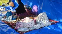 Sebuah keluarga beristirahat di tenda setelah gempa berkekuatan 6,2 di Mamuju, Senin (18/1/2021). Sebanyak 27.850 jiwa telah mengungsi di sejumlah posko pengungsian karena rumah mereka rusak akibat gempa. (AFP/Adek Berry)