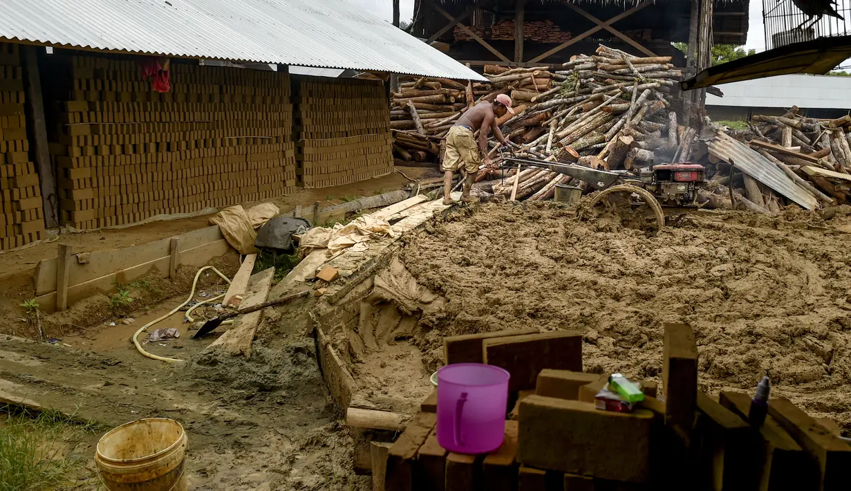 Seorang pria mencampur bahan untuk membuat batu bata di sebuah pabrik batu bata di pinggiran Kajhu, Provinsi Aceh (18/11/2020). (AFP/Chaideer Mahyuddin)
