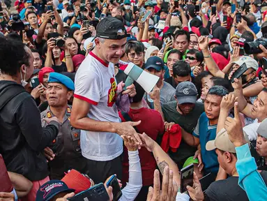 Bakal calon presiden dari PDIP yang juga Gubernur Jawa Tengah Ganjar Pranowo (tengah) menyapa pendukungnya saat berolahraga di Kompleks Stadion Utama Gelora Bung Karno (SUGBK), Jakarta, Minggu (30/4/2023). (Liputan6.com/Faizal Fanani)