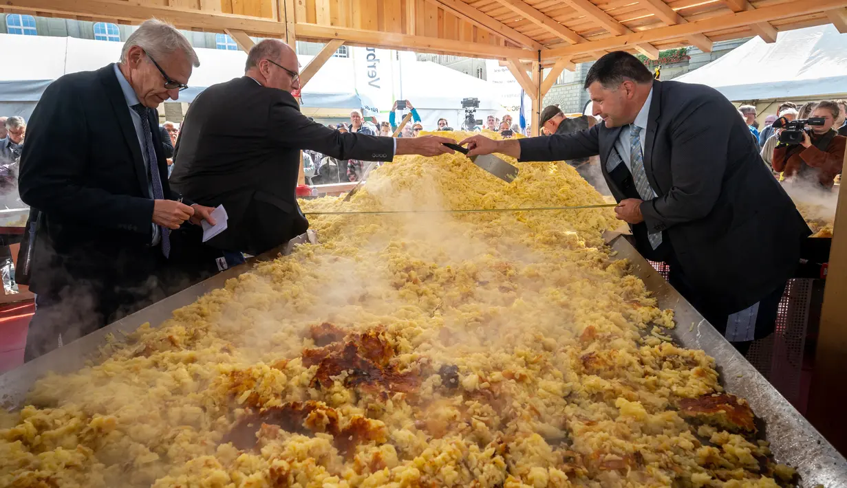 Para pejabat mengukur penggorengan raksasa selama upaya rekor rösti terbesar di dunia sebagai bagian dari acara yang menandai peringatan 125 tahun Serikat Petani Swiss (SBV) di Bern, Swiss pada 19 September 2022. Meski merupakan makanan khas dari wilayah berbahasa Jerman di Swiss, rosti kini dipandang sebagai makanan nasional negara Eropa itu. (Fabrice COFFRINI / AFP)