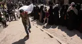 Seorang pria Palestina membawa sekantong tepung, sementara yang lain menunggu di depan titik distribusi yang didirikan oleh Save Youth Future Society (SYFS), yang bekerja sama dengan Program Pangan Dunia PBB (WFP), di Kota Gaza pada 26 Juni 2025. (BASHAR TALEB/AFP)