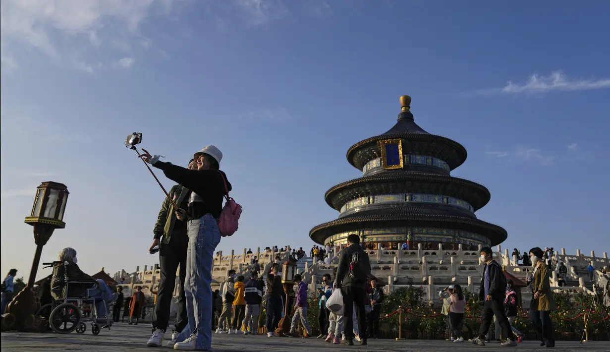 Para wanita berfoto selfie saat pengunjung mengunjungi Kuil Surga pada hari terakhir Hari Nasional China selama seminggu di Beijing, Kamis (7/10/2021). (AP Photo/Andy Wong)