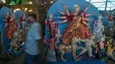 Seniman berjalan melewati patung Dewi Durga jelang Festival Durga Puja di Gauhati, India, Jumat (16/10/2020). Para pejabat kesehatan memperingatkan tentang potensi penyebaran COVID-19 selama musim festival keagamaan dengan pertemuan besar di kuil dan distrik perbelanjaan. (AP Photo/Anupam Nath)