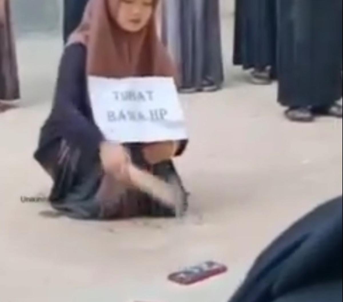 Santriwati ini dengan pasrah menghancurkan hp miliknya di depan ustaz dan teman-temannya.<br><br>Usai dipukul beberapa kali,  hp miliknya pun  retak. Santriwati ini nampak menahan rasa sedihnya.