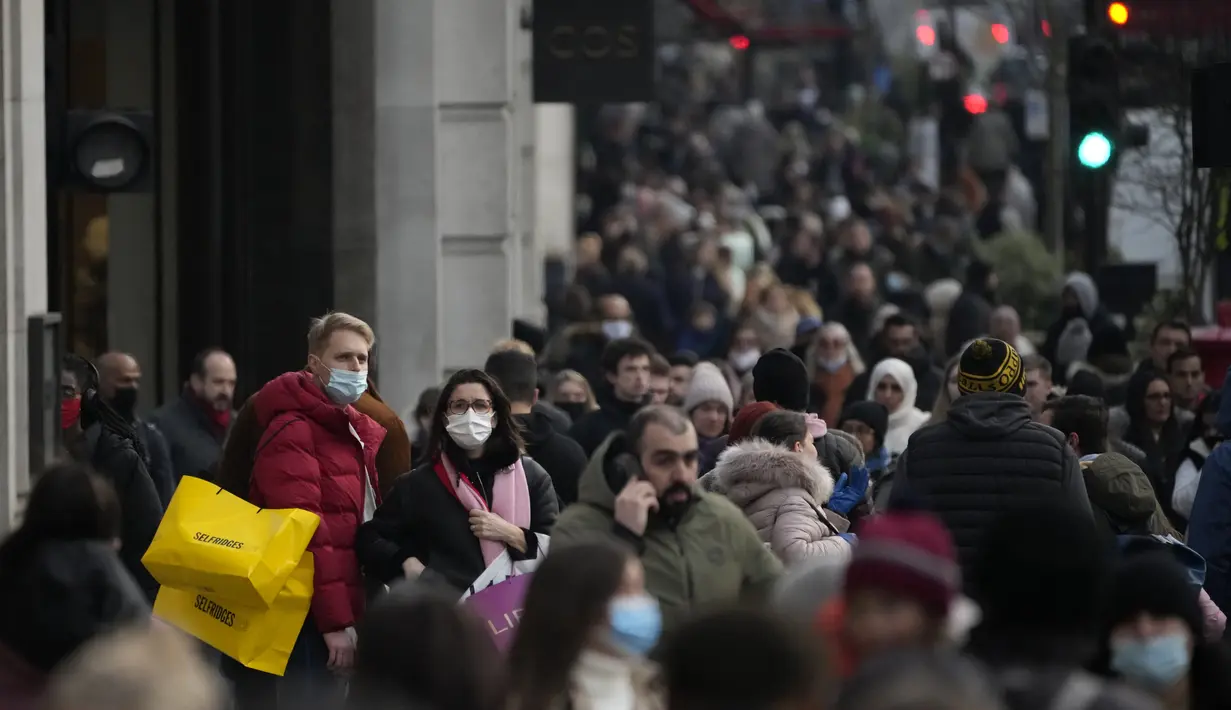 Orang-orang berdiri memegang tas belanja di Regent Street di London, Senin (29/11/2021). Di Inggris, kewajiban mengenakan masker akan berlaku lagi di toko-toko dan transportasi umum mulai Selasa menyusul temuan Covid-19 varian Omicron. (AP Photo/Matt Dunham)
