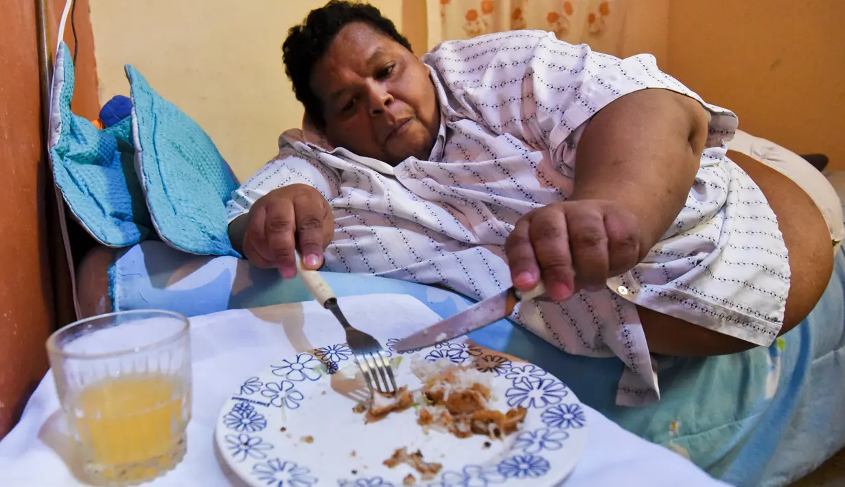 Oscar Vasquez Morales (44) saat makan siang di rumahnya di Palmira, Kolombia, 19 Maret 2016. Dengan bobot tubuh hampir 400 kg, Oscar membutuhkan bantuan orang lain untuk melakukan berbagai kegiatannya sehari-hari. (AFP PHOTO/Luis ROBAYO)
