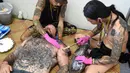 Seniman saat membuat tato pengunjung pria saat acara Bali Tattoo Expo 2017 di pulau resor Indonesia, Denpasar, Bali (12/5). Acara ini digelar selama 3 hari, mulai (12/5/2017) sampai (14/5/2017). (AFP Photo/Sonny Tumbelaka)