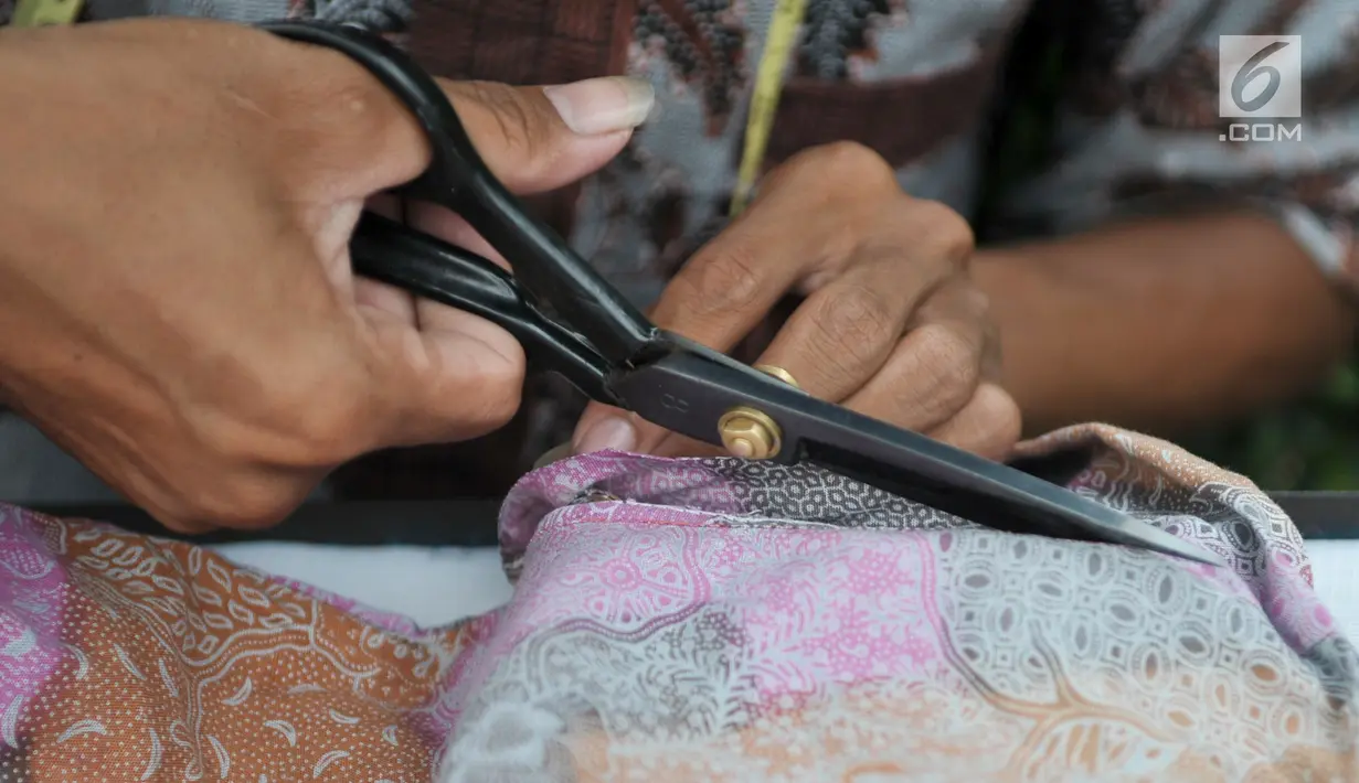 Penjahit memotong pakaian pelanggannya yang akan dirombak model dan ukurannya, Jakarta, Kamis (22/6). Jelang lebaran, penjahit keliling mulai banyak menerima orderan warga untuk sekedar memotong atau mengecilkan pakaian. (Liputan6.com/Yoppy Renato)