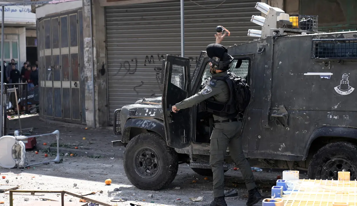 Seorang paramiliter petugas polisi perbatasan Israel melemparkan gas air mata ke warga Palestina saat bentrokan di Kota Nablus, Tepi Barat, 22 Februari 2023. Menurut Kementerian Kesehatan Palestina setidaknya 102 orang terluka, 82 terkena peluru tajam dan enam berada dalam kondisi kritis. (AP Photo/Majdi Mohammed)