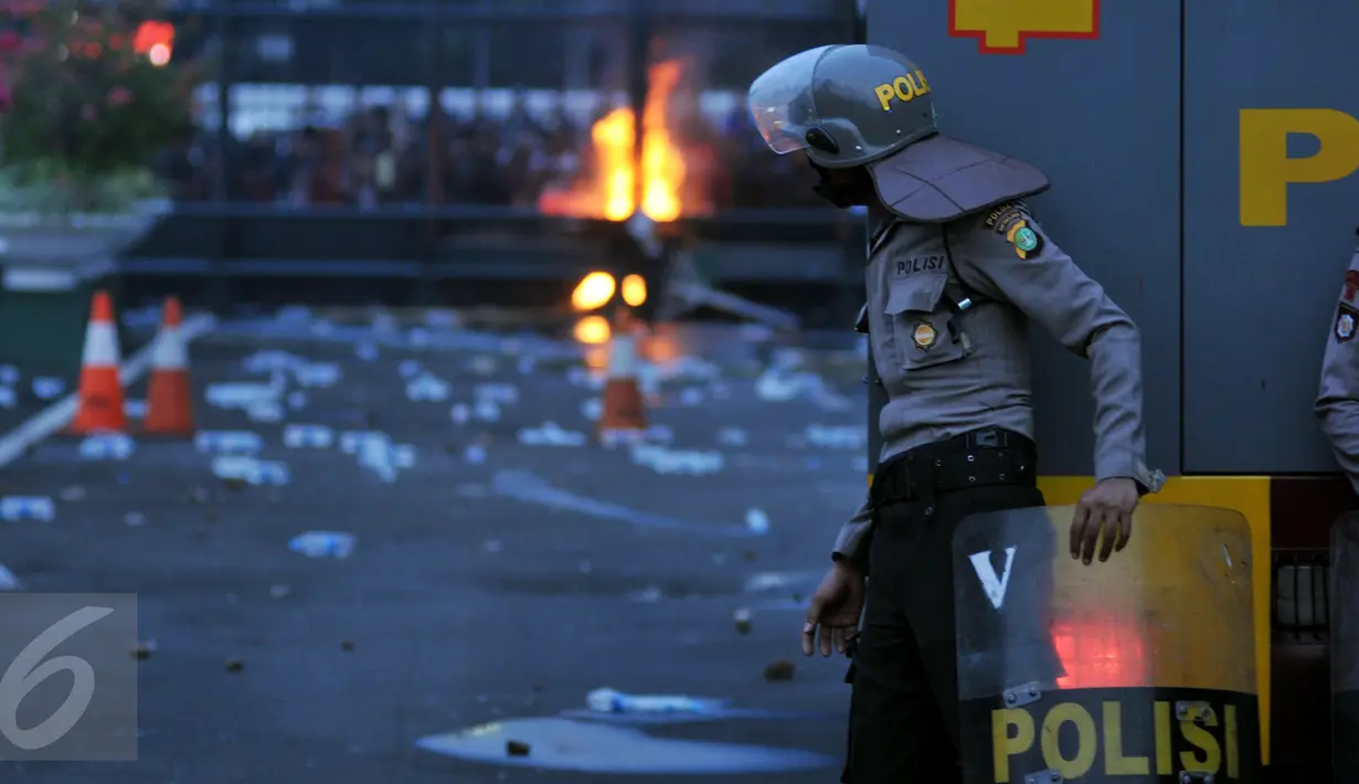 Seorang petugas mengamati aksi mahasiswa memperingati Hari Sumpah Pemuda di depan Gedung DPR, Senayan, Jakarta, Rabu (28/10/2015). Dalam aksinya para mahasiswa membakar ban. (Liputan6.com/Johan Tallo) 