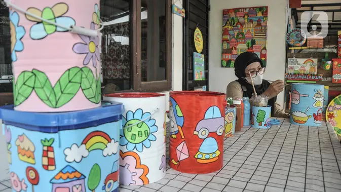Lani (48) saat menyelesaikan gambar yang dilukis pada sebuah kaleng bekas di workshop Kaleng Lani, Tanah Baru, Beji, Depok, Jawa Barat, Minggu (5/6/2022). Harga produk kerajinan karya Lani pun cukup terjangkau, mulai Rp25.000 hingga Rp300.000 per buah yang dipasarkan melalui media sosial dan galeri. (merdeka.com/Iqbal S Nugroho)