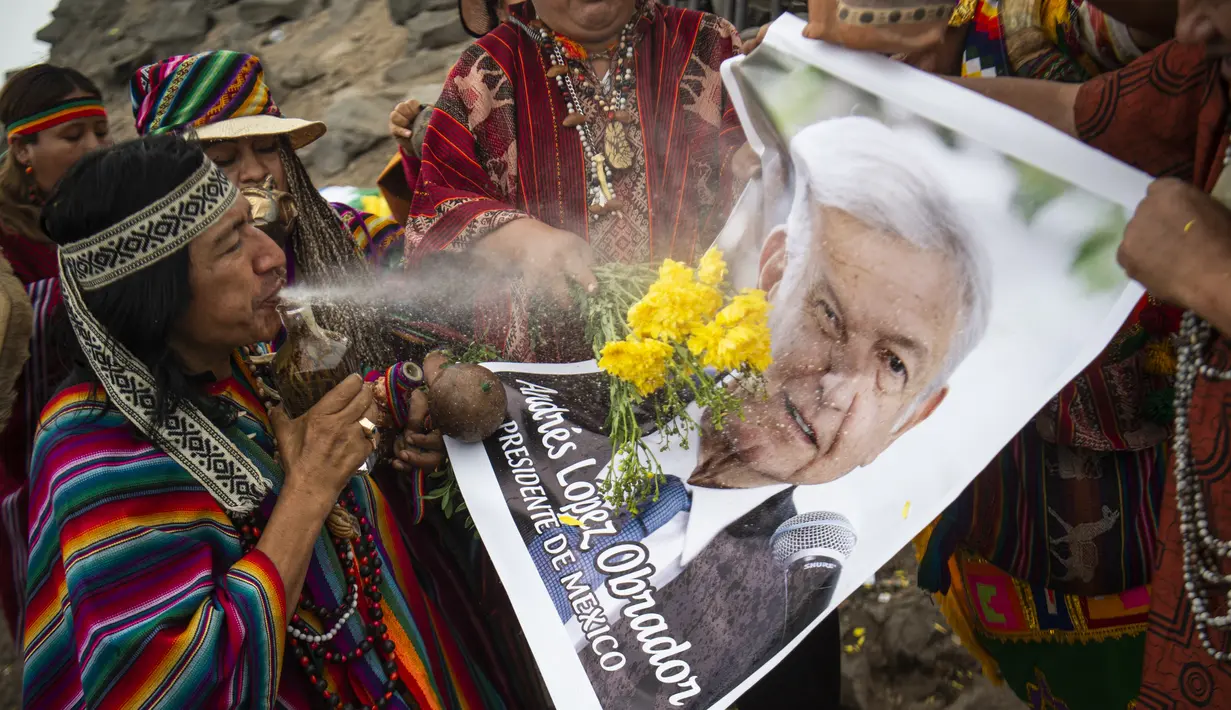 Dukun Peru menyemprotkan air ke foto Presiden Meksiko Andres Manuel Lopez Obrador saat memberikan prediksi untuk 2022 dalam ritual tradisional sebelum Malam Tahun Baru di bukit San Cristobal di Lima, Peru  (29/12/2021). (AFP/Ernesto Benavides)