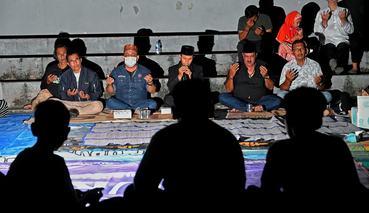 Sejumlah warga menghadiri upacara doa pada malam peringatan 17 tahun tsunami Boxing Day 2004 di monumen Kapal Tsunami Lampulo di Banda Aceh (25/12/2021). (AFP/Chaideer Mahyuddin)