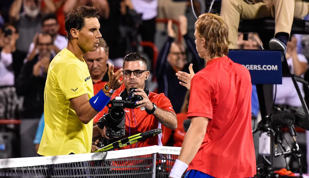 Petenis Spanyol, Rafael Nadal mengucapkan selamat kepada petenis Kanada, Denis Shapovalov seusai turnamen Piala Rogers di Montreal, Kamis (10/8). Nadal disingkirkan petenis 18 tahun itu dengan skor 6-3, 4-6, 6-7. (MINAS PANAGIOTAKIS/GETTY IMAGES/AFP)
