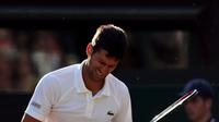Petenis Serbia, Novak Djokovic meringis kesakitan saat melawan Tomas Berdych (Ceko) pada perempatfinal Wimbledon 2017, Rabu (12/7). Melawan Berdych cedera Djokovic kambuh, ia  terlihat mengalami masalah dengan cedera lengannya. (Gareth Fuller/PA via AP)